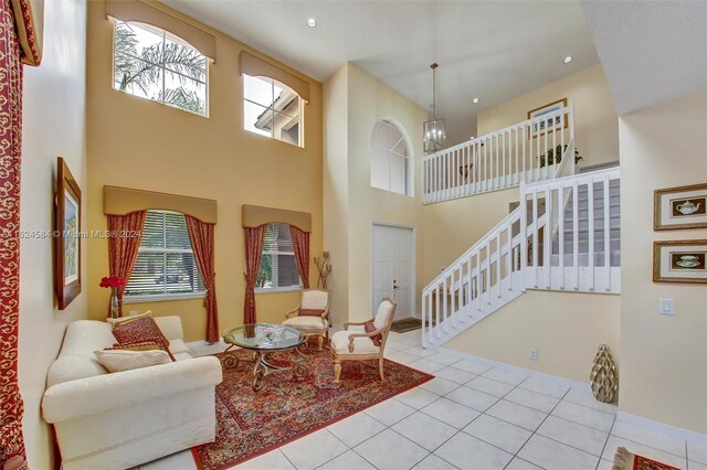 living room with light tile patterned flooring, a notable chandelier, a wealth of natural light, and a towering ceiling