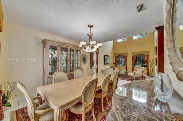 dining area featuring an inviting chandelier, tile patterned flooring, and a textured ceiling