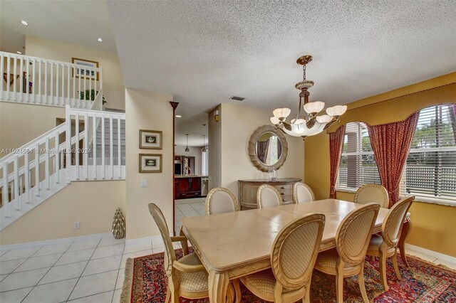 tiled dining room featuring an inviting chandelier and a textured ceiling