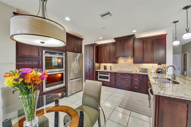 kitchen featuring light tile patterned flooring, sink, light stone counters, appliances with stainless steel finishes, and backsplash