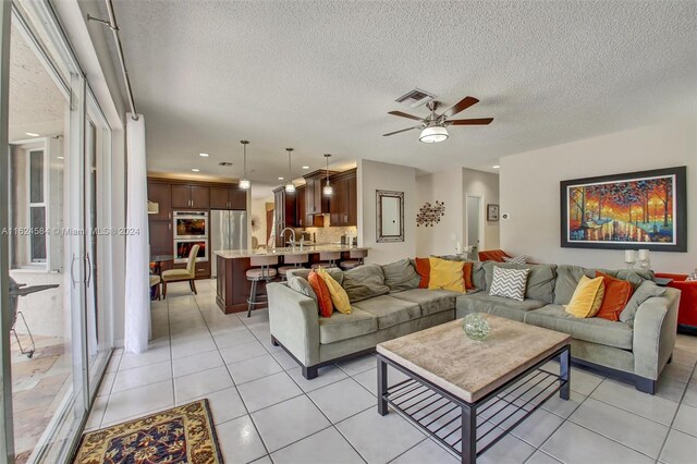 tiled living room with a textured ceiling, sink, and ceiling fan