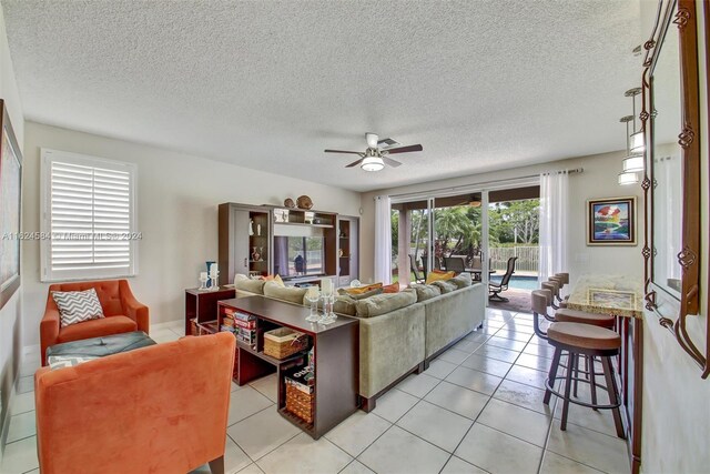 living room with a textured ceiling, ceiling fan, and light tile patterned floors