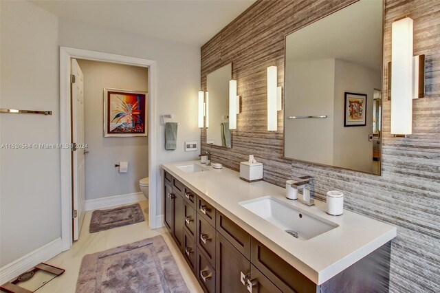 bathroom featuring tile patterned flooring, backsplash, double sink vanity, and toilet