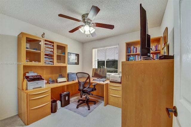 office area featuring built in desk, a textured ceiling, light colored carpet, and ceiling fan