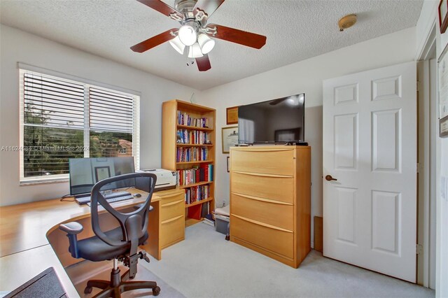 carpeted office space featuring a textured ceiling and ceiling fan