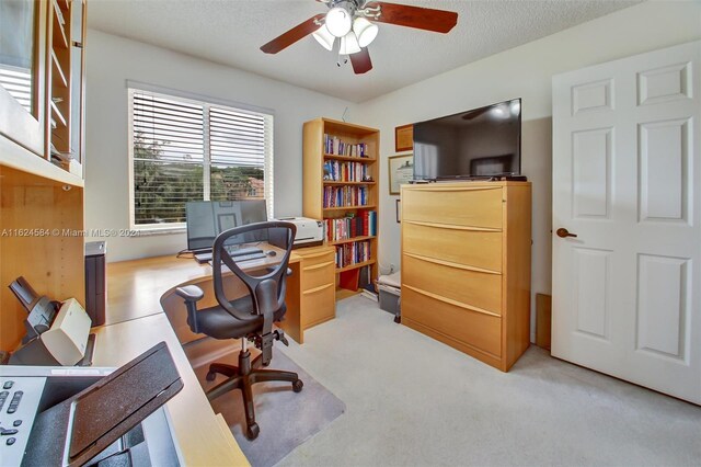 carpeted office space featuring a textured ceiling and ceiling fan