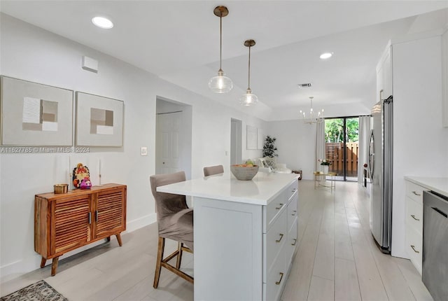 kitchen with a kitchen island, appliances with stainless steel finishes, pendant lighting, a breakfast bar area, and white cabinets