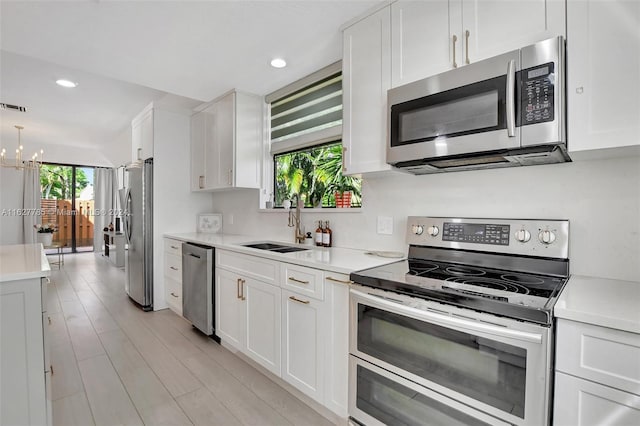 kitchen featuring stainless steel appliances, white cabinetry, and sink