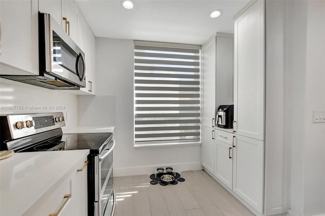 kitchen featuring stainless steel appliances, white cabinetry, and light wood-type flooring