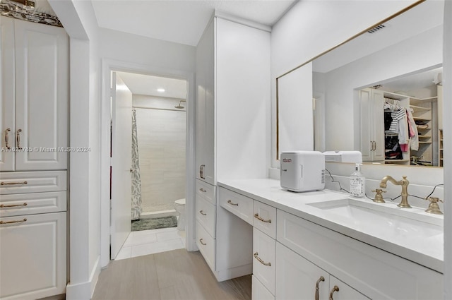 bathroom with a tile shower, vanity, and toilet