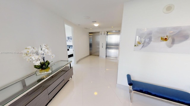 hallway featuring elevator and light tile patterned floors