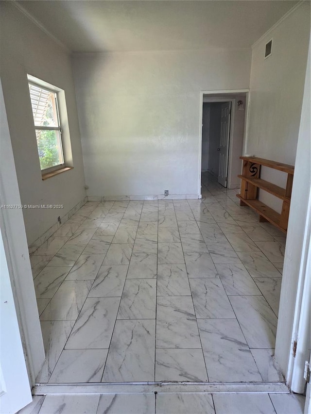 empty room featuring visible vents, marble finish floor, and crown molding