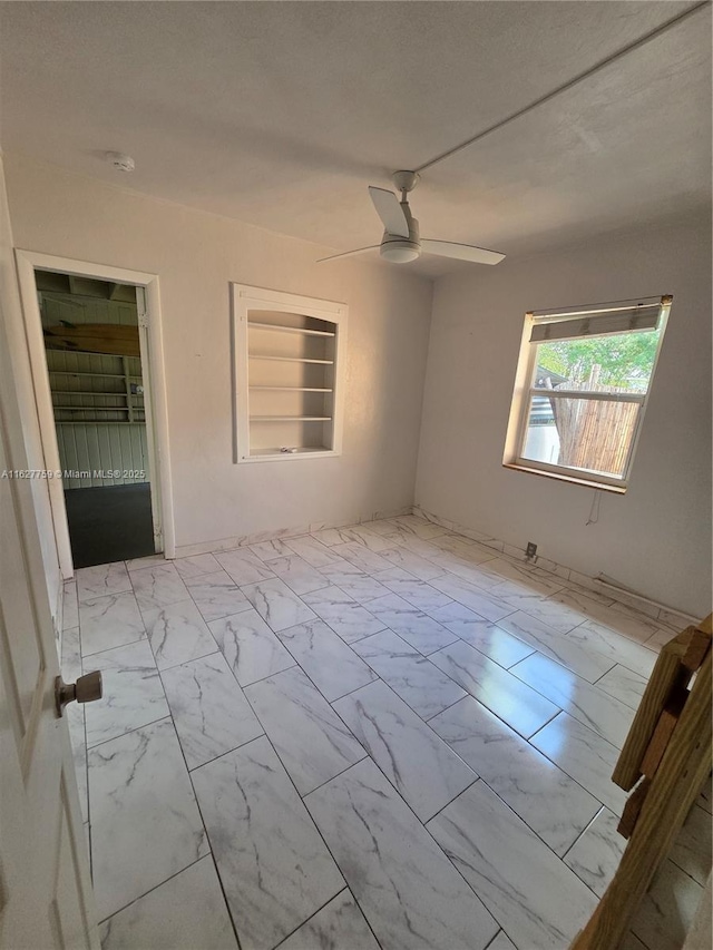 unfurnished room featuring marble finish floor and a ceiling fan