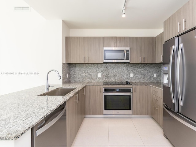 kitchen with light stone countertops, sink, stainless steel appliances, and tasteful backsplash