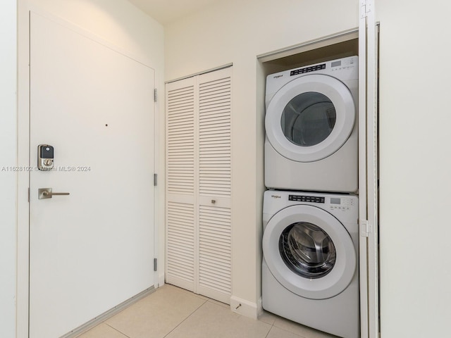 laundry room featuring light tile patterned flooring and stacked washing maching and dryer