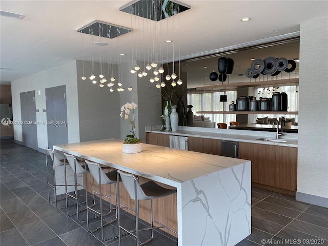 bar with decorative light fixtures, light stone countertops, dark tile patterned flooring, and sink