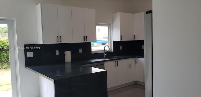 kitchen featuring white cabinets, dishwasher, decorative backsplash, and sink