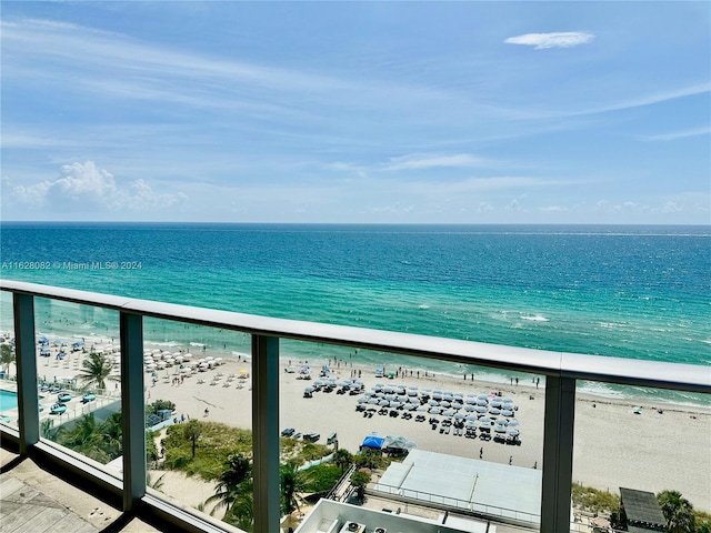 balcony featuring a view of the beach and a water view