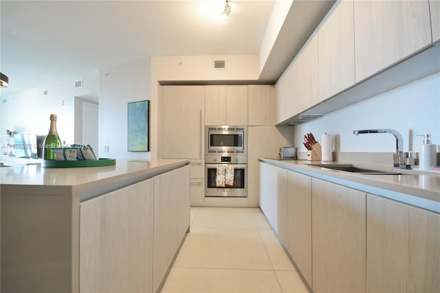 kitchen featuring appliances with stainless steel finishes, light tile patterned floors, light brown cabinetry, and sink