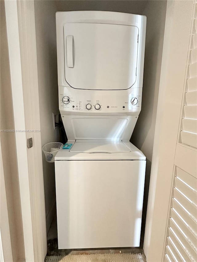 clothes washing area with light carpet and stacked washer / dryer