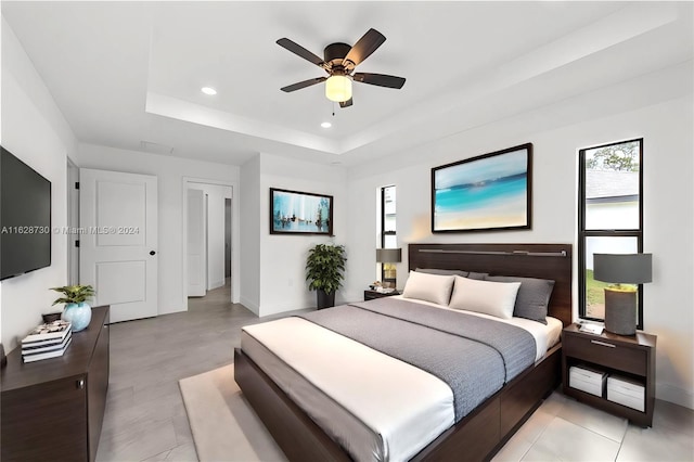 bedroom with ceiling fan and a tray ceiling