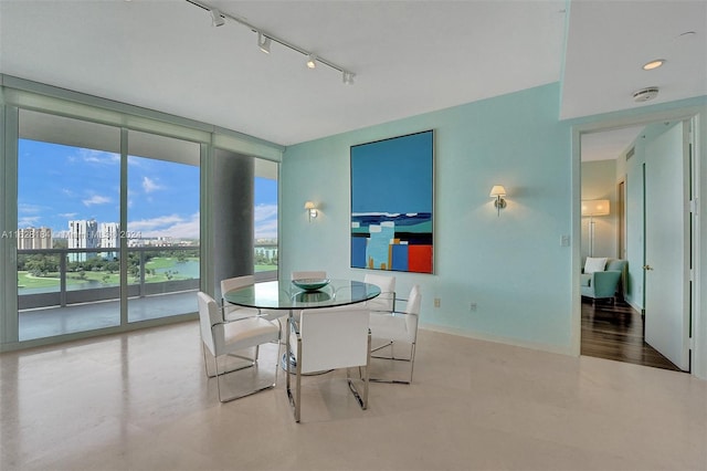 dining space featuring a wall of windows, hardwood / wood-style flooring, and track lighting