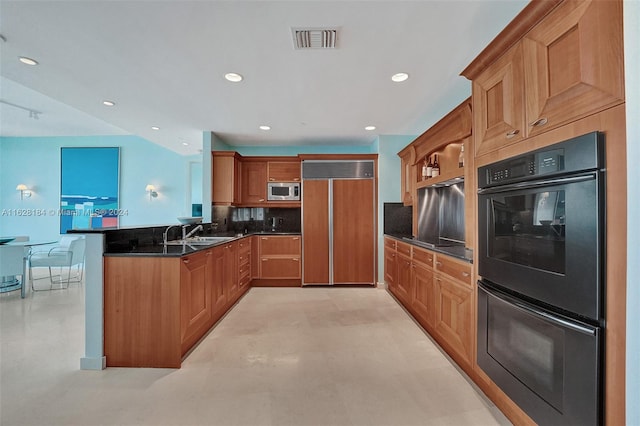 kitchen featuring dark stone countertops, kitchen peninsula, backsplash, built in appliances, and sink