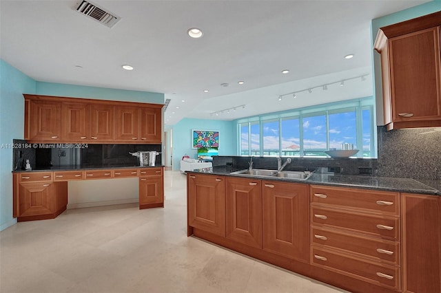 kitchen featuring sink, dark stone countertops, decorative backsplash, and light tile patterned floors