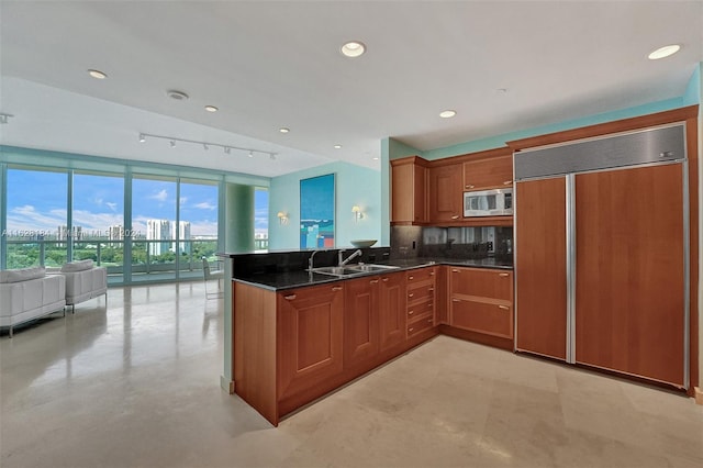 kitchen featuring decorative backsplash, sink, fridge, kitchen peninsula, and track lighting