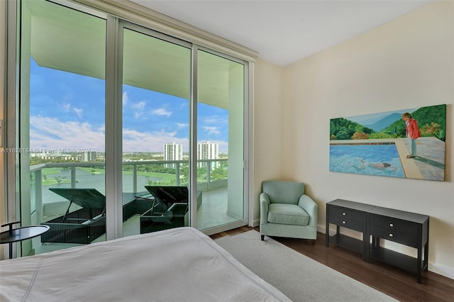 bedroom featuring dark wood-type flooring, floor to ceiling windows, and access to outside