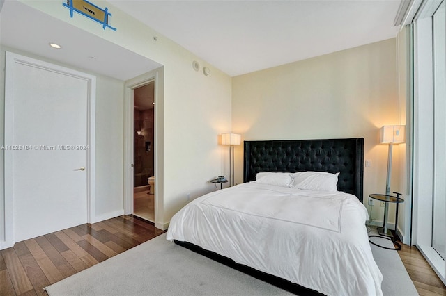 bedroom featuring ensuite bath and wood-type flooring