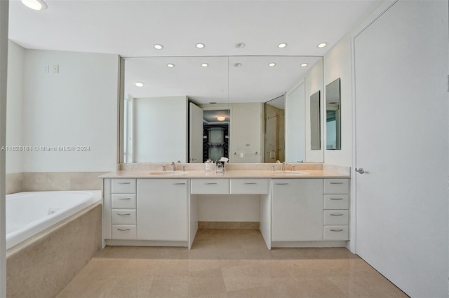 bathroom with tile patterned flooring, tiled tub, and double vanity