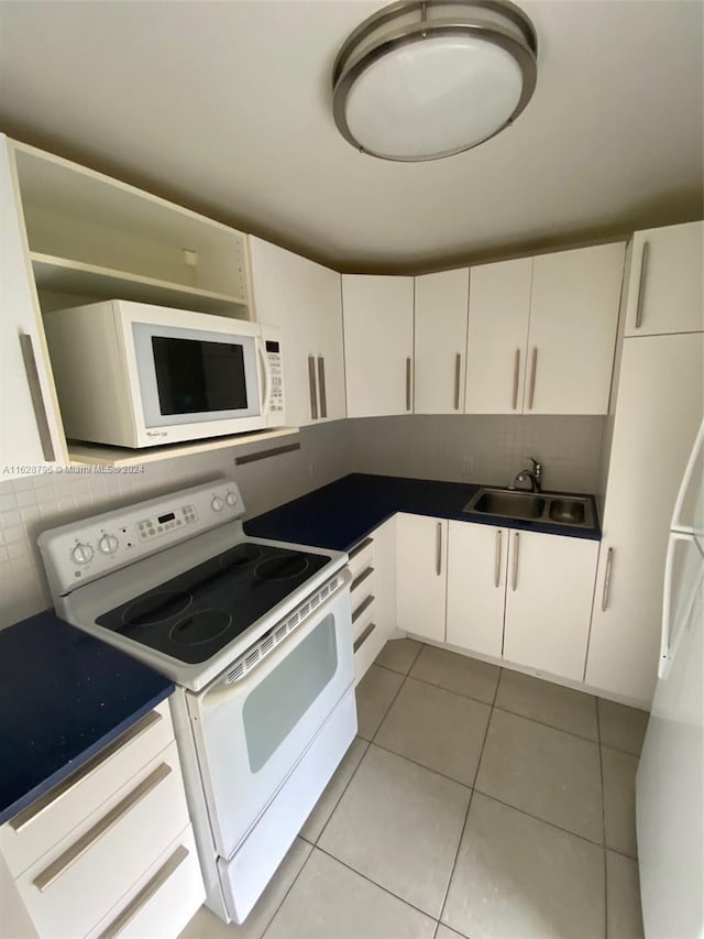 kitchen with white appliances, tasteful backsplash, sink, white cabinets, and light tile patterned flooring