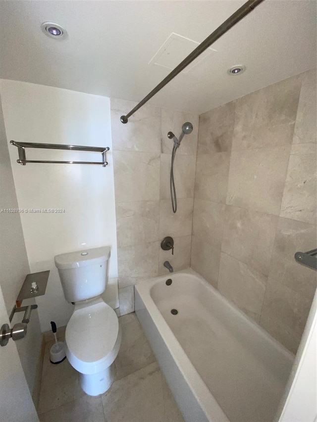 bathroom with tiled shower / bath combo, toilet, and tile patterned flooring