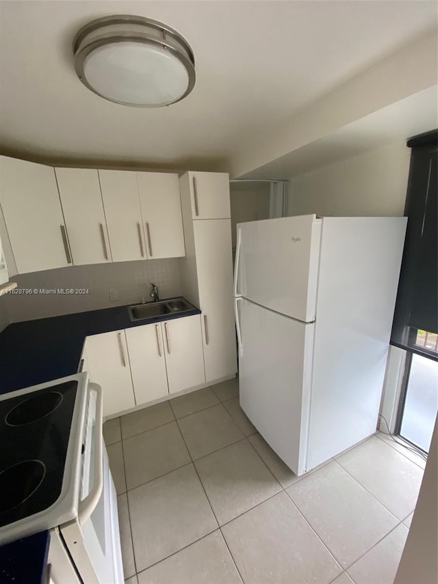 kitchen with white appliances, light tile patterned floors, white cabinetry, and sink