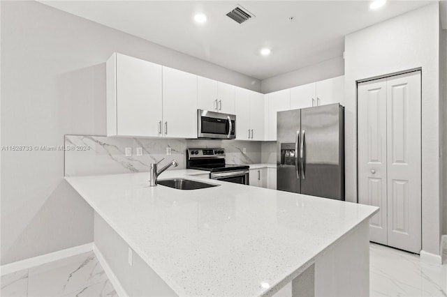 kitchen featuring appliances with stainless steel finishes, kitchen peninsula, sink, and white cabinets