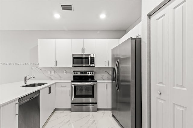 kitchen featuring white cabinets, stainless steel appliances, backsplash, and sink