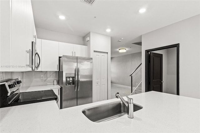 kitchen with white cabinets, sink, kitchen peninsula, backsplash, and stainless steel appliances