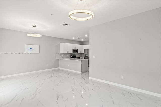 interior space with pendant lighting, tasteful backsplash, white cabinets, kitchen peninsula, and appliances with stainless steel finishes