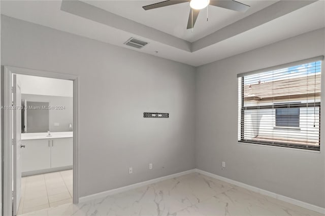 spare room with ceiling fan and a tray ceiling