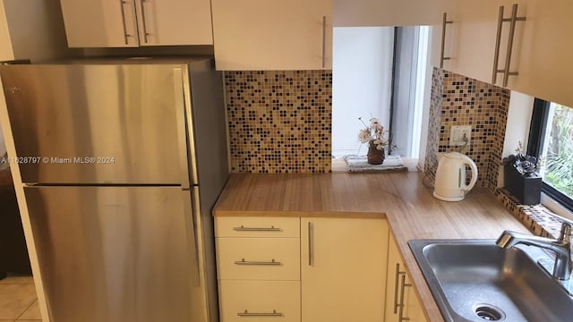 kitchen with stainless steel fridge, sink, and tasteful backsplash