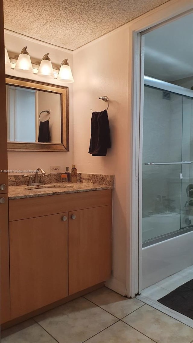 bathroom with tile patterned flooring, vanity, shower / bath combination with glass door, and a textured ceiling