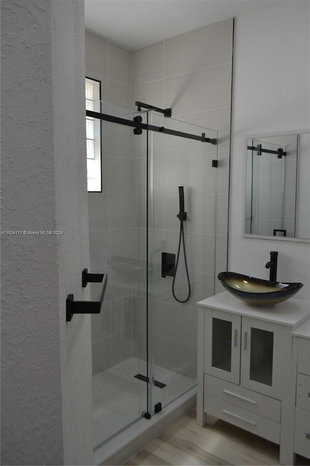 bathroom featuring a shower with shower door, vanity, and wood-type flooring