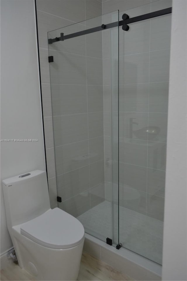 bathroom featuring hardwood / wood-style floors, toilet, and an enclosed shower