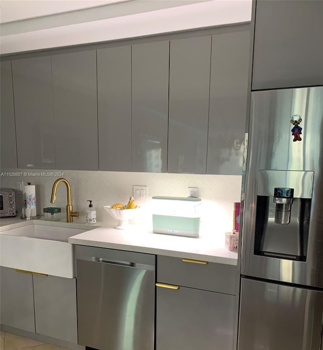 kitchen with tasteful backsplash, stainless steel appliances, gray cabinets, and sink