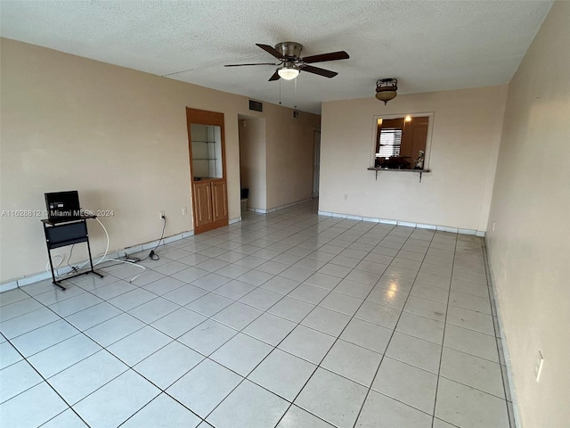 spare room with a textured ceiling, ceiling fan, and light tile patterned floors