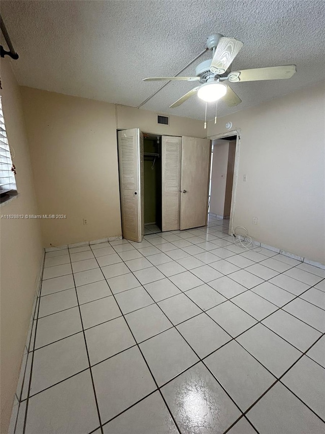 unfurnished bedroom with a textured ceiling, ceiling fan, and light tile patterned floors