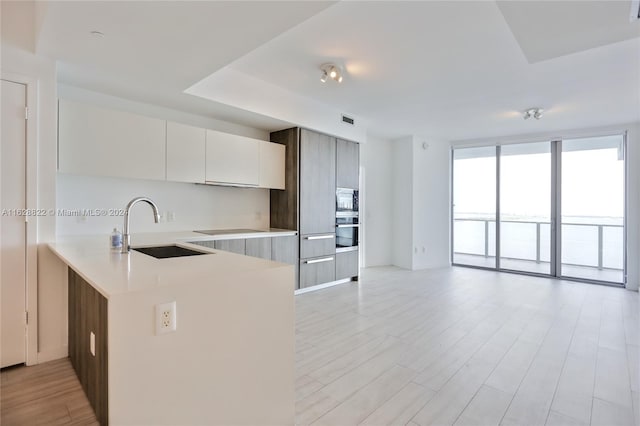 kitchen featuring sink, white cabinets, stainless steel appliances, and light hardwood / wood-style floors