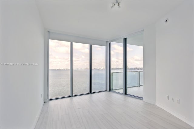 unfurnished room featuring expansive windows, a water view, and plenty of natural light