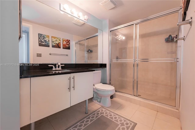 bathroom with tile patterned flooring, vanity, toilet, and a shower with shower door